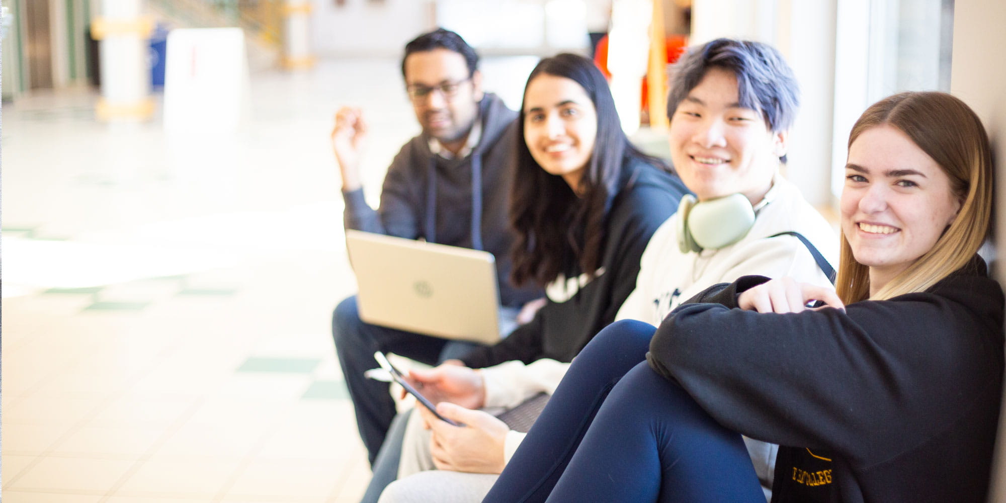 Four students sitting in a hallway