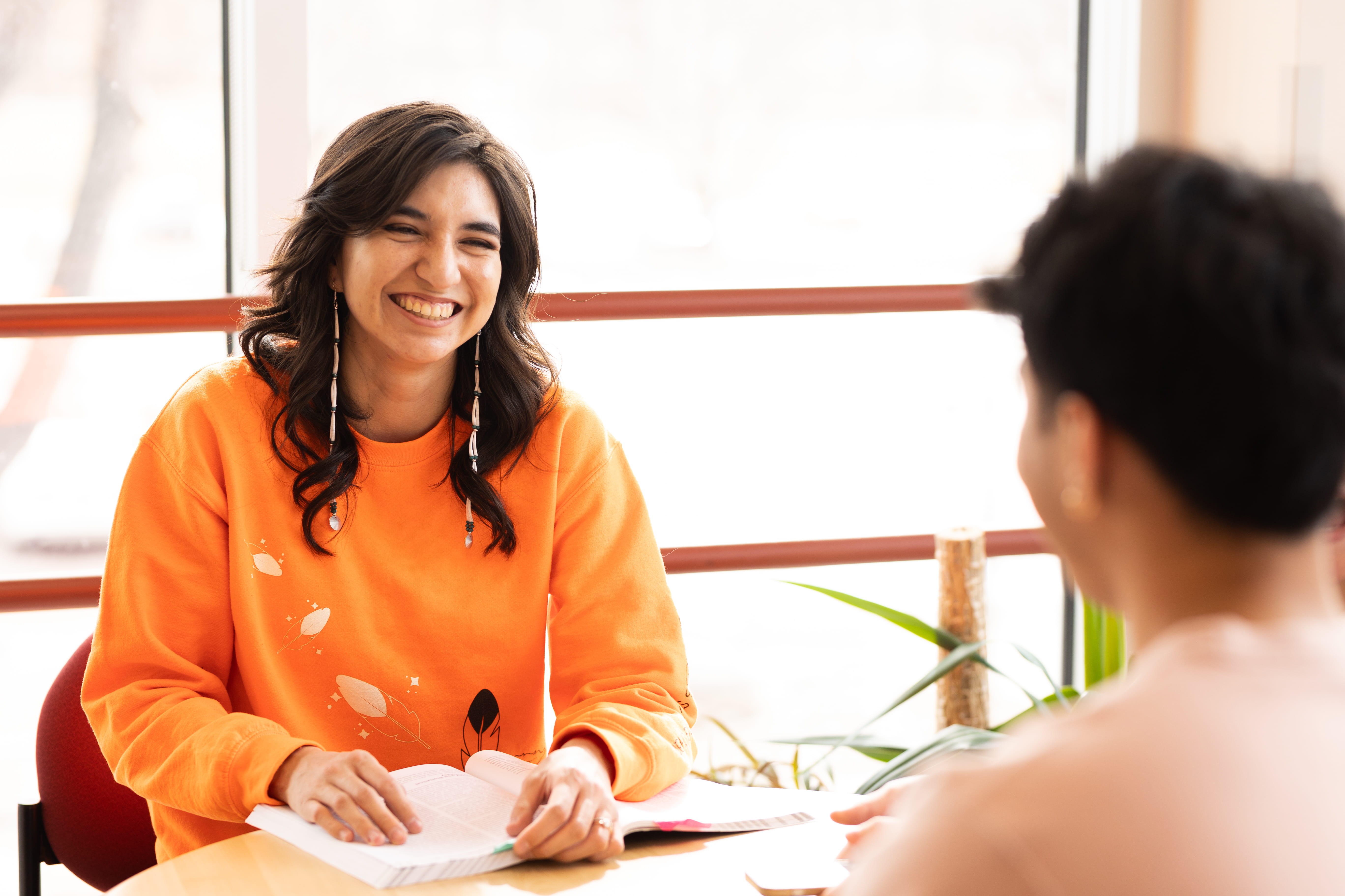 Two students studying together at table near window
